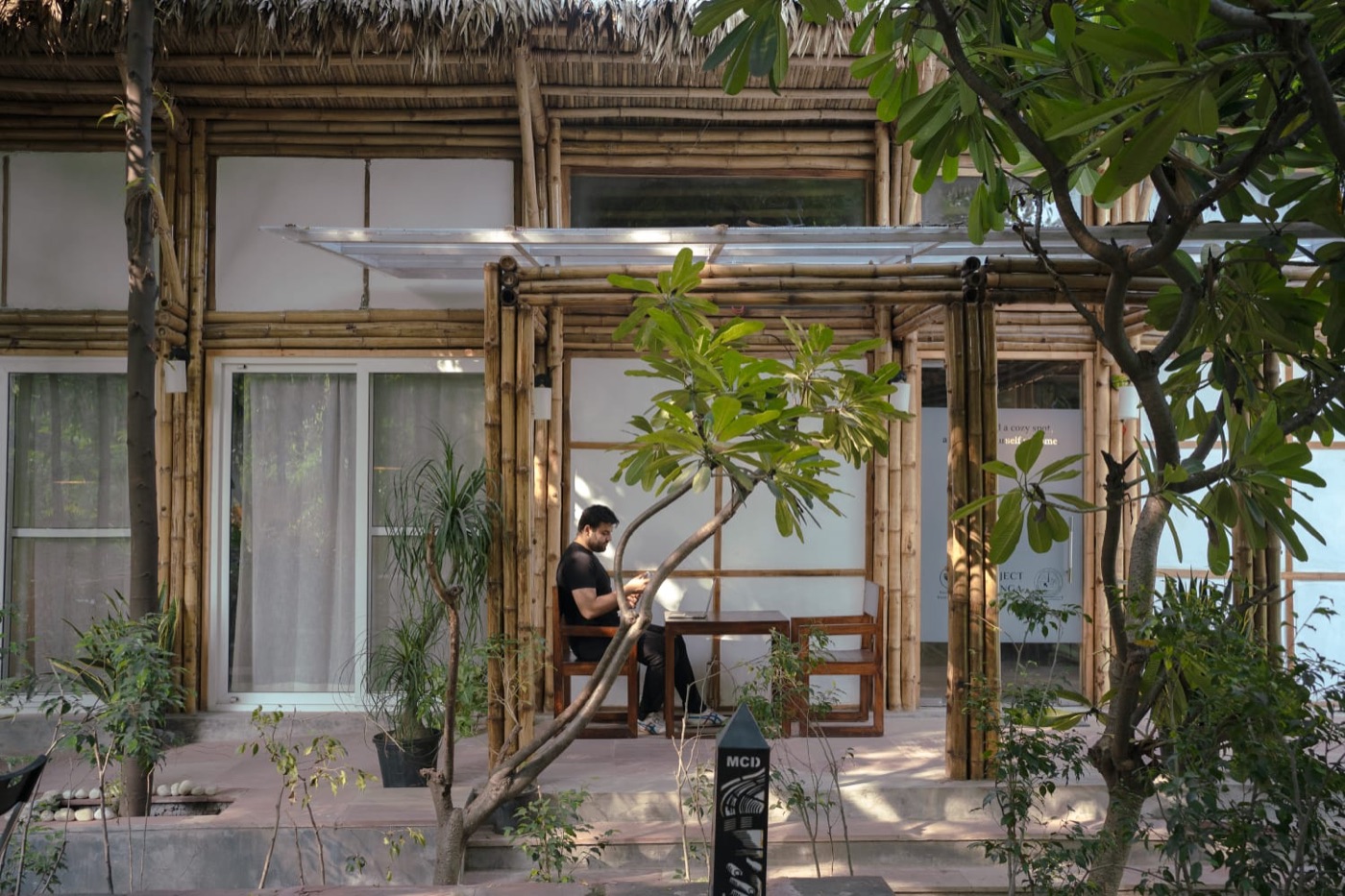 Project Otenga: the courtyard under the Pilkhan tree, the bamboo-and-thatch structure, and the signed wall (4 of 4)